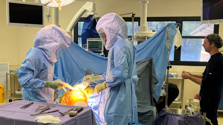 Surgeons in sterile hoods performing a joint replacement in theatre.