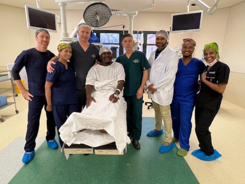 The surgical team gathered around a patient in theatre at Busamed Hillcrest after a joint replacement.